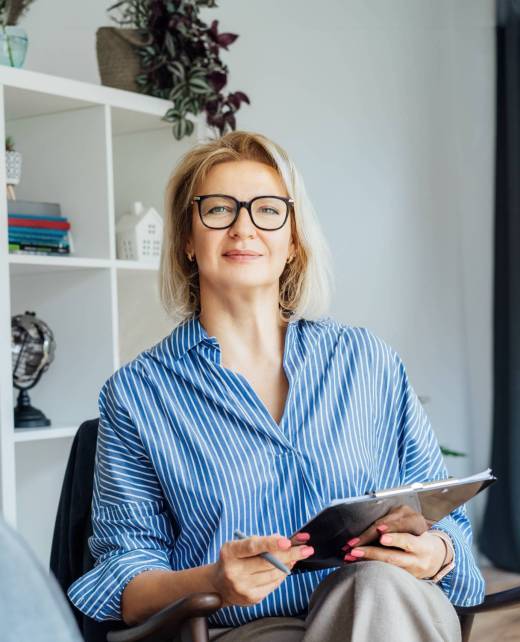 Professional Psychotherapy. Successful female Psychologist Smiling To Camera Sitting On armchair In Office. Mature 50s middle-aged professional portrait of teacher, coach, mentor, therapist, counselor